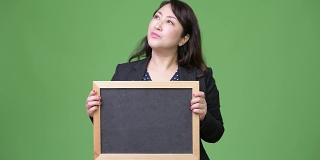 成熟美丽的亚洲女商人一边展示黑板一边思考