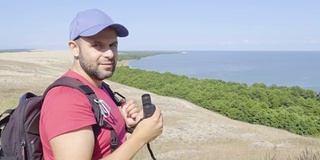 用双筒望远镜观察野生动物的旅行者。男人们在度假中观赏自然景观。一个背包旅行者正在用双筒望远镜看大海，看美丽的风景。山。海滩。