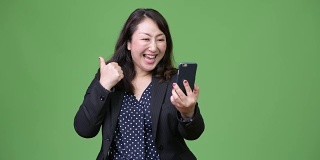成熟美丽的亚洲女商人使用手机竖起大拇指