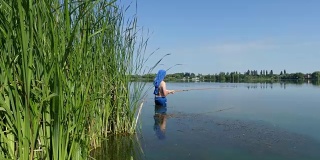 一个人拿着钓竿在湖边钓鱼。渔民们在阳光下站在湖边。