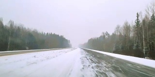 在可怕的多雪多风的天气里，重型货车在公路上行驶。透过挡风玻璃的视野-驾驶员视角。移动视频。