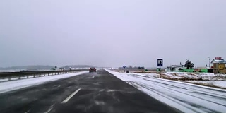 在可怕的多雪多风的天气里在高速公路上开车。透过挡风玻璃的视野-驾驶员视角。移动视频。