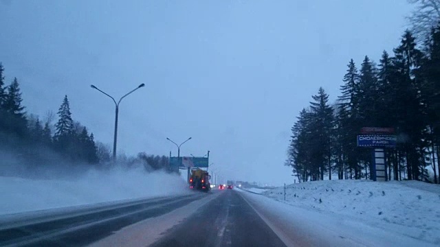 环卫车在可怕的多雪多风的夜晚清理高速公路。透过挡风玻璃的视野-驾驶员视角。移动视频。