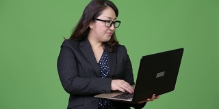 成熟美丽的亚洲商人在绿色背景下使用笔记本电脑
