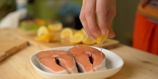一个女孩在煎鲑鱼排前撒上柠檬汁