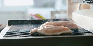 新鲜的鱼排在热腾腾的烤架上炸着，散发着烟熏的香味