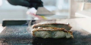 新鲜的鱼排在热腾腾的烤架上炸着，散发着烟熏的香味