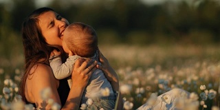 一个年轻快乐的母亲和孩子在一个花田在日落的慢镜头。