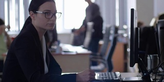 压力管理，疲惫的女商人戴着眼镜，手持铅笔，坐在办公室的办公桌上用电脑工作