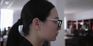 沮丧疲惫的女孩戴着眼镜在办公室里想一些工作的近景