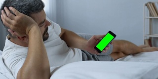 男人在智能手机上滚动绿色屏幕的网页，寻找新的应用程序