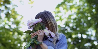 年轻貌美的女子欣赏着牡丹花的花束