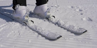 在一个阳光明媚的日子里，滑雪者踩进滑雪绑定与他的滑雪靴