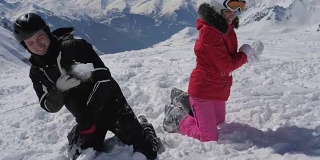 在高山度假村，一对兴高采烈的滑雪者在玩雪球