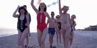 快乐的朋友们穿着泳衣和烟雾弹在海边享受暑假