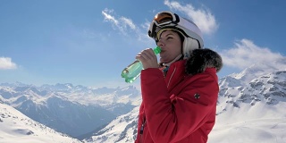 女子滑雪饮用干净的水从一个塑料瓶在一个山的背景