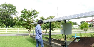 农学家农民使用平板电脑监测太阳能电池在农场抽水。利用移动应用技术进行农业电源管理