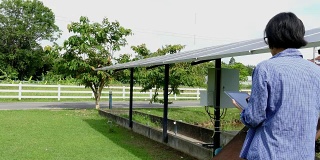 农学家农民使用平板电脑监测太阳能电池在农场抽水。利用移动应用技术进行农业电源管理