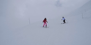 两名女子滑雪者在冬季山坡上同步转弯雕刻滑雪