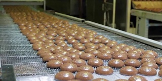 蛋糕在自动传送带或流水线上，在糖果烹饪工厂或工厂烘烤过程中。食品工业、甜饼等甜面包材料的生产