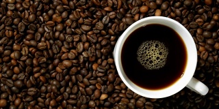 白杯子里的黑咖啡，堆在一堆烘好的咖啡豆上