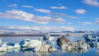 4k时间移动的云与蓝色冰山漂浮在Jokulsarlon冰湖，冰岛视频素材模板下载