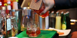 调酒师在酒吧用酒杯混合鸡尾酒，靠近侍者的手将酒精饮料倒入玻璃杯