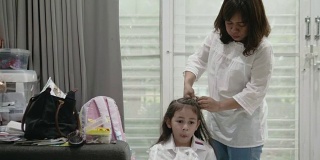 母亲在上学前给女儿编头发。