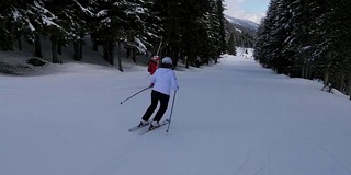 两个运动女子滑雪者在山上滑雪在森林下坡