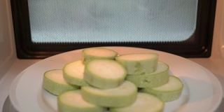 用微波炉煮蔬菜。微波炉内的生西葫芦切片