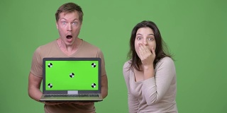 年轻夫妇展示笔记本电脑，同时看起来震惊在一起