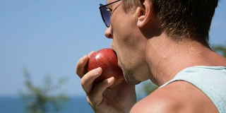 一个男人正在吃一个红苹果。