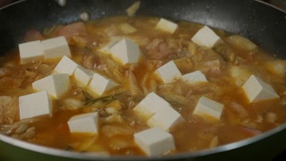 沸腾的泡菜Jjigae。有辣泡菜、豆腐和其他配料的韩式汤。视频素材模板下载