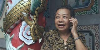 神社:年长的亚洲妇女正在打手机。