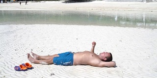 那个男人躺在海边的沙滩上抽烟