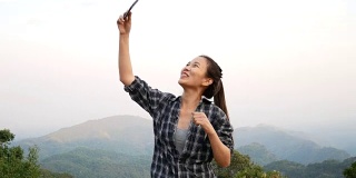 4 k。美丽的亚洲女性使用智能手机在户外进行视频聊天，与朋友分享旅游自然景观，或通过社交媒体直播。