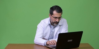 英俊的波斯胡子男子医生使用笔记本电脑