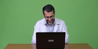 英俊的波斯胡子男子医生思考时使用笔记本电脑