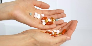 五颜六色的维生素和药片在女孩的手中。制药、健康饮食。从一只手到另一只手倒