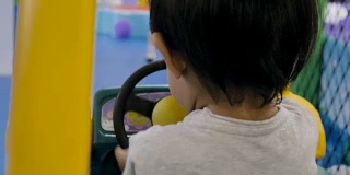 亚洲小男孩骑着一辆玩具车