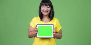 美丽快乐的亚洲女人展示数字平板电脑