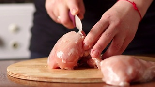 特写女子用陶瓷刀切鸡肉。视频素材模板下载