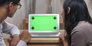 两个人在看绿色屏幕的笔记本电脑