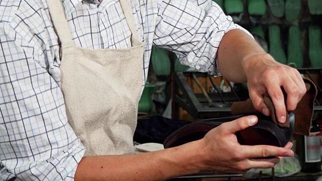 Shoemaker polishing leather shoes with a piece of soft cloth