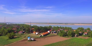 空中滑块拍摄了一个沿着河边的小村庄，沿途有电线穿过景观