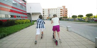 孩子们在阳光明媚的夏日学习骑滑板车。孩子们在户外玩滑板车。儿童积极的休闲和户外运动