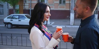 调情，时髦的女人和男人聊天，用塑料杯在镇上的街道上喝茶