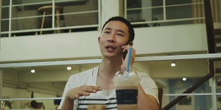 一名泰国男子在咖啡馆边用智能手机边讨论他的工作