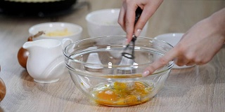 女厨师在厨房桌子上的玻璃碗里打鸡蛋