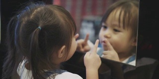 泰国女孩使她的脸幽默的镜子反射